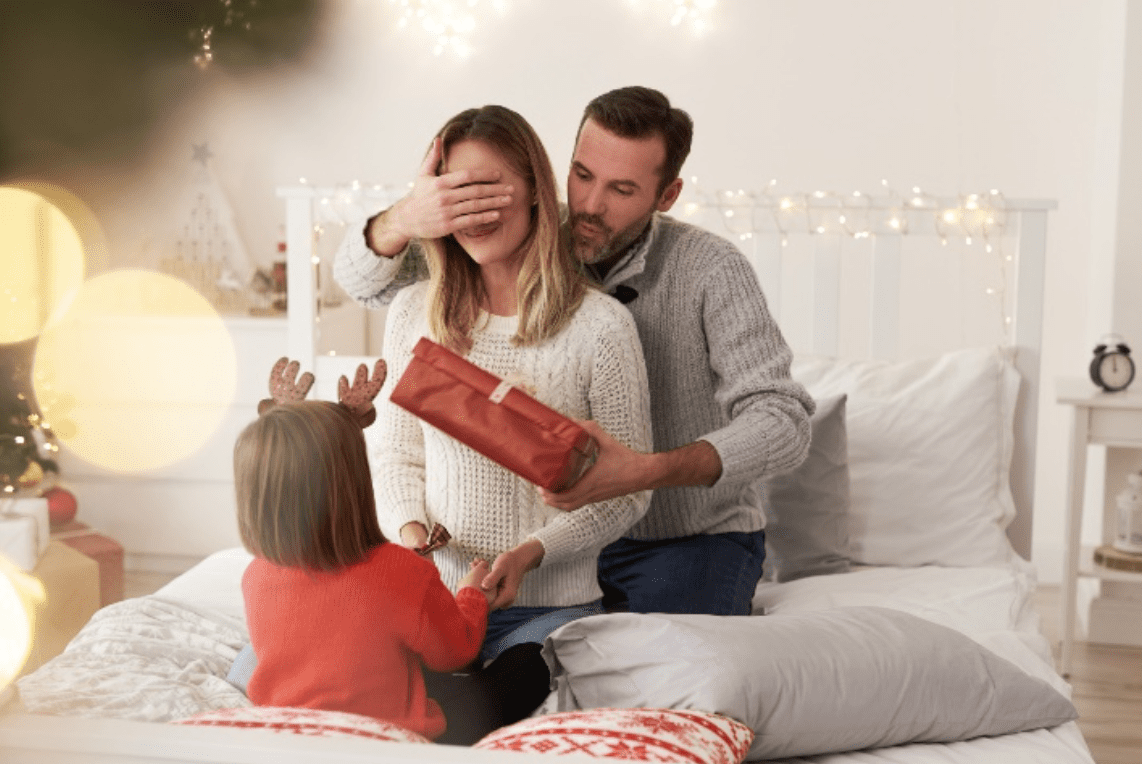 A man and woman giving a girl a present