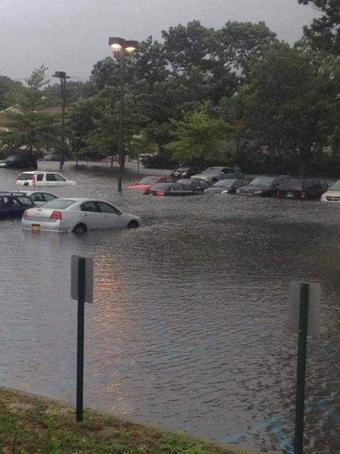 A flooded parking lot with cars parked in it.