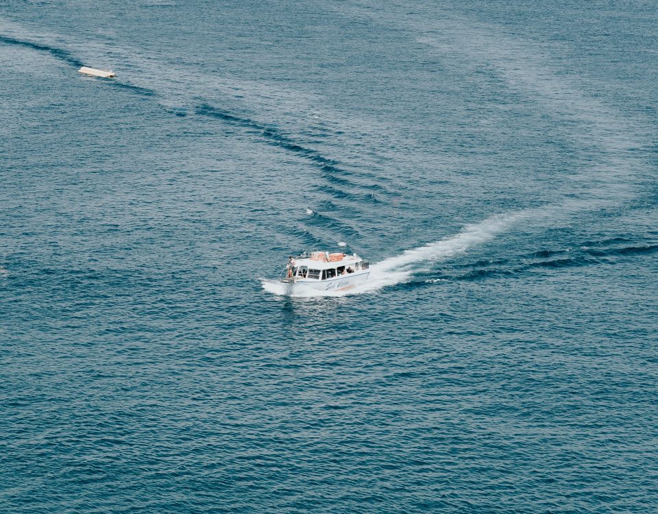 A boat is traveling through the water near some boats.