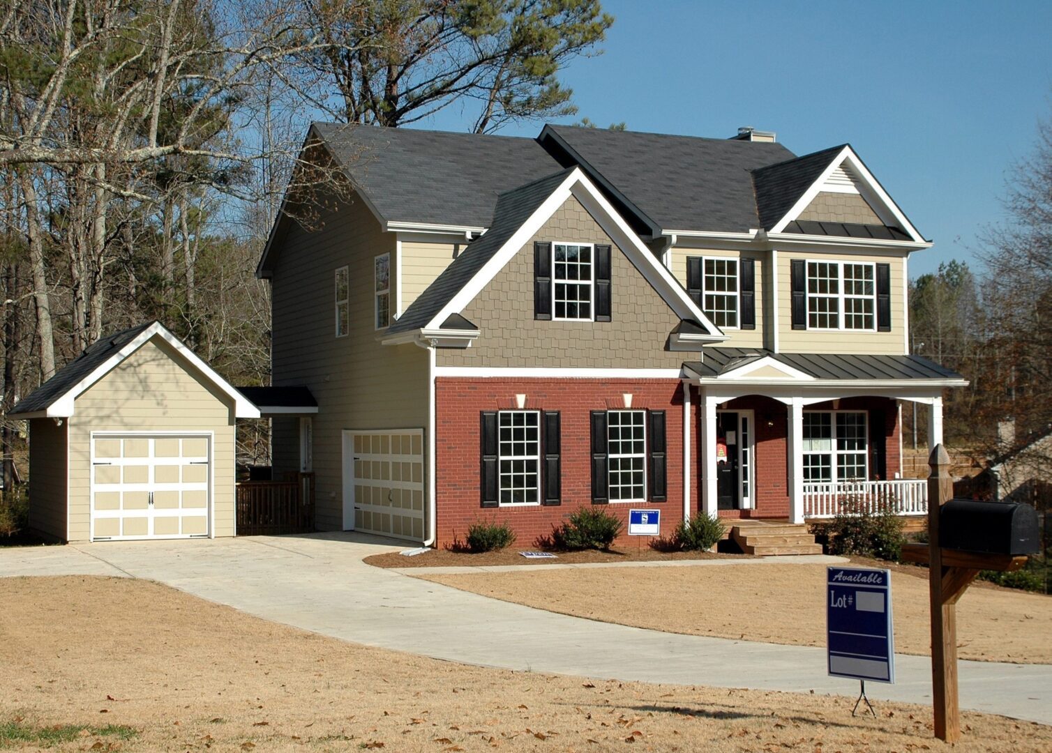 A house with two garage doors and a sign in front of it.