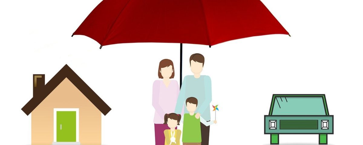 A family under an umbrella in front of their home.